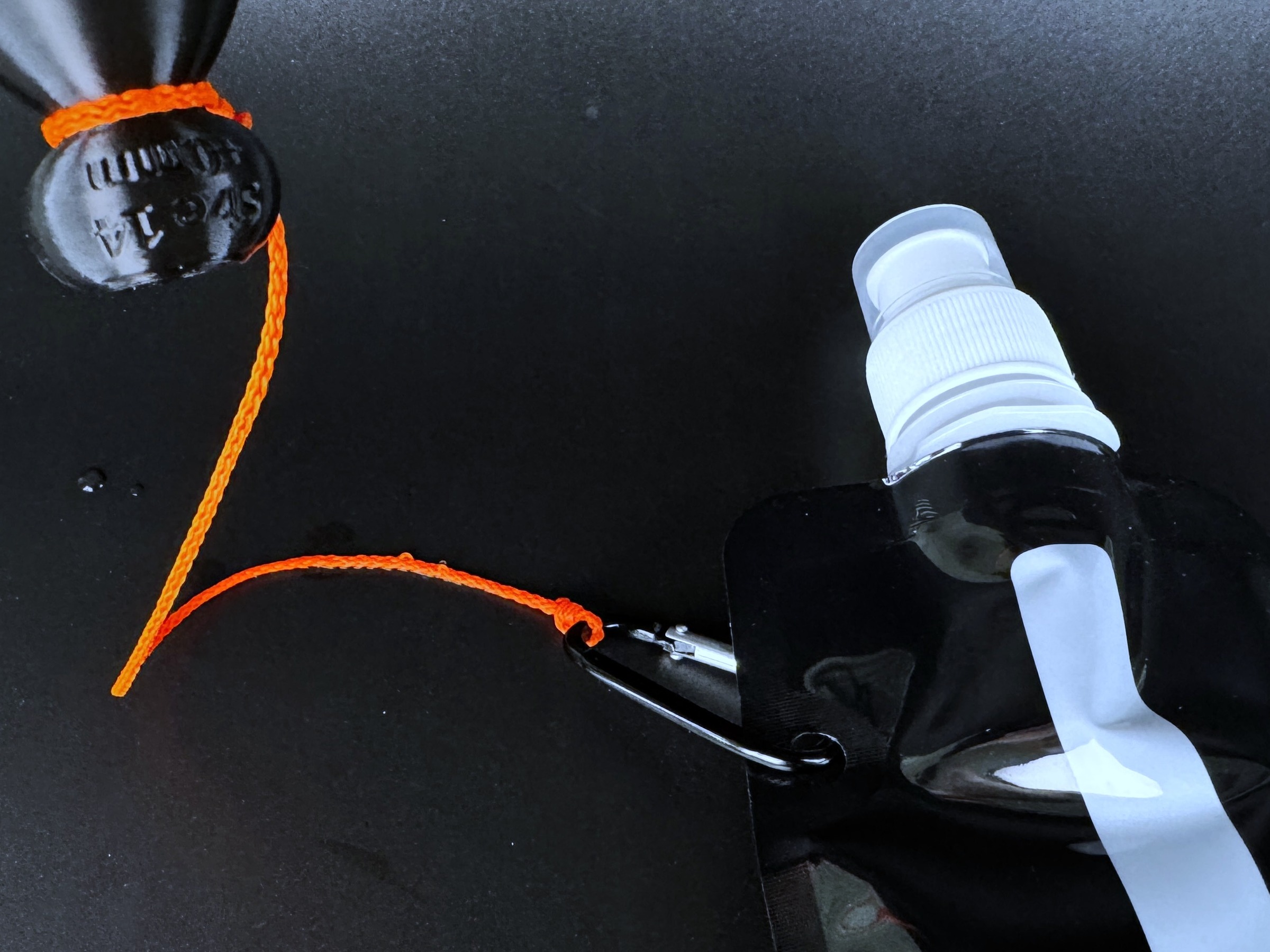 Tugging string clipped by carabiner to the collapsible water bottle, with a demo P-tainer at the other end.