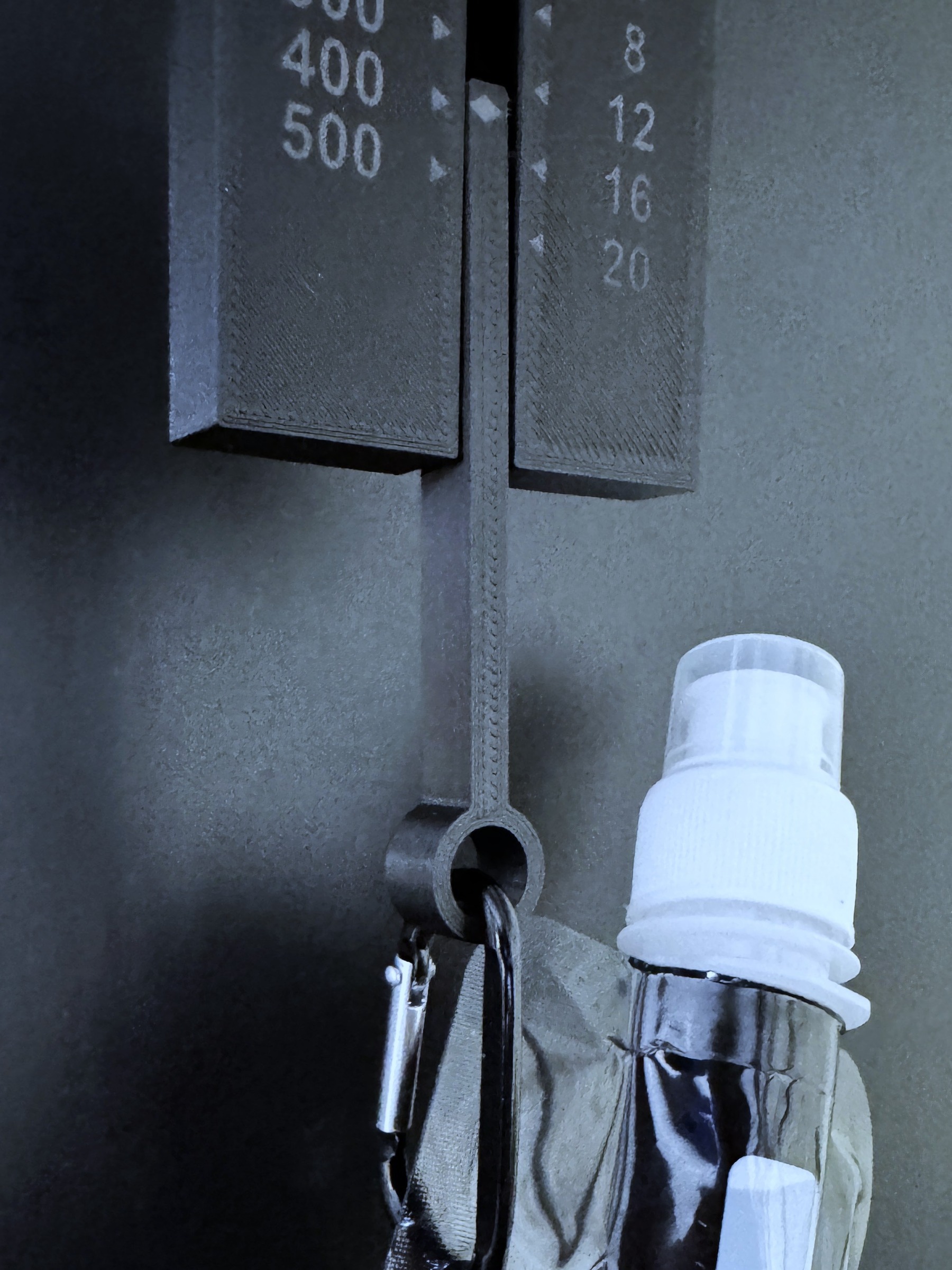 Close-up of the weight gauge showing its gram and ounce scales, with a water bottle hanging from it.