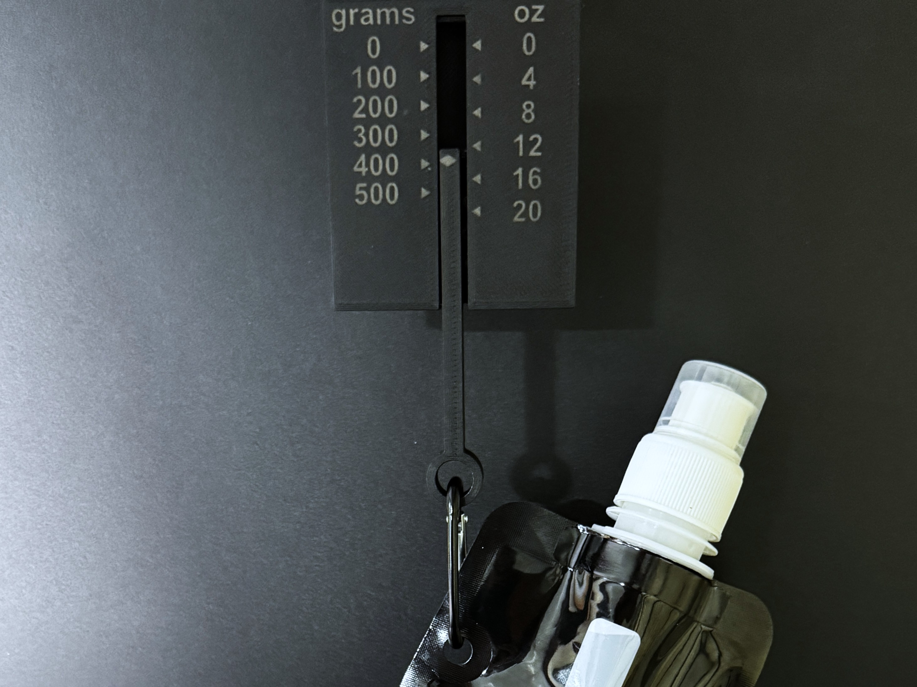 A collapsible water bottle clipped by its carabiner to the hanging tension gauge.