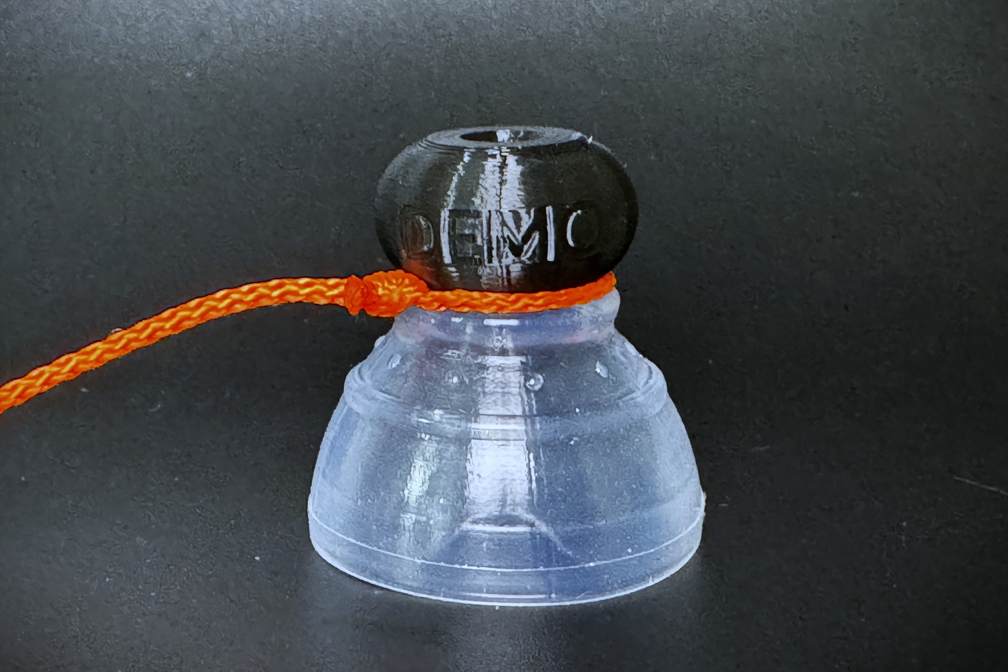 A demo P-tainer with a gripper fitted and the tugging string looped around the threaded knob end.