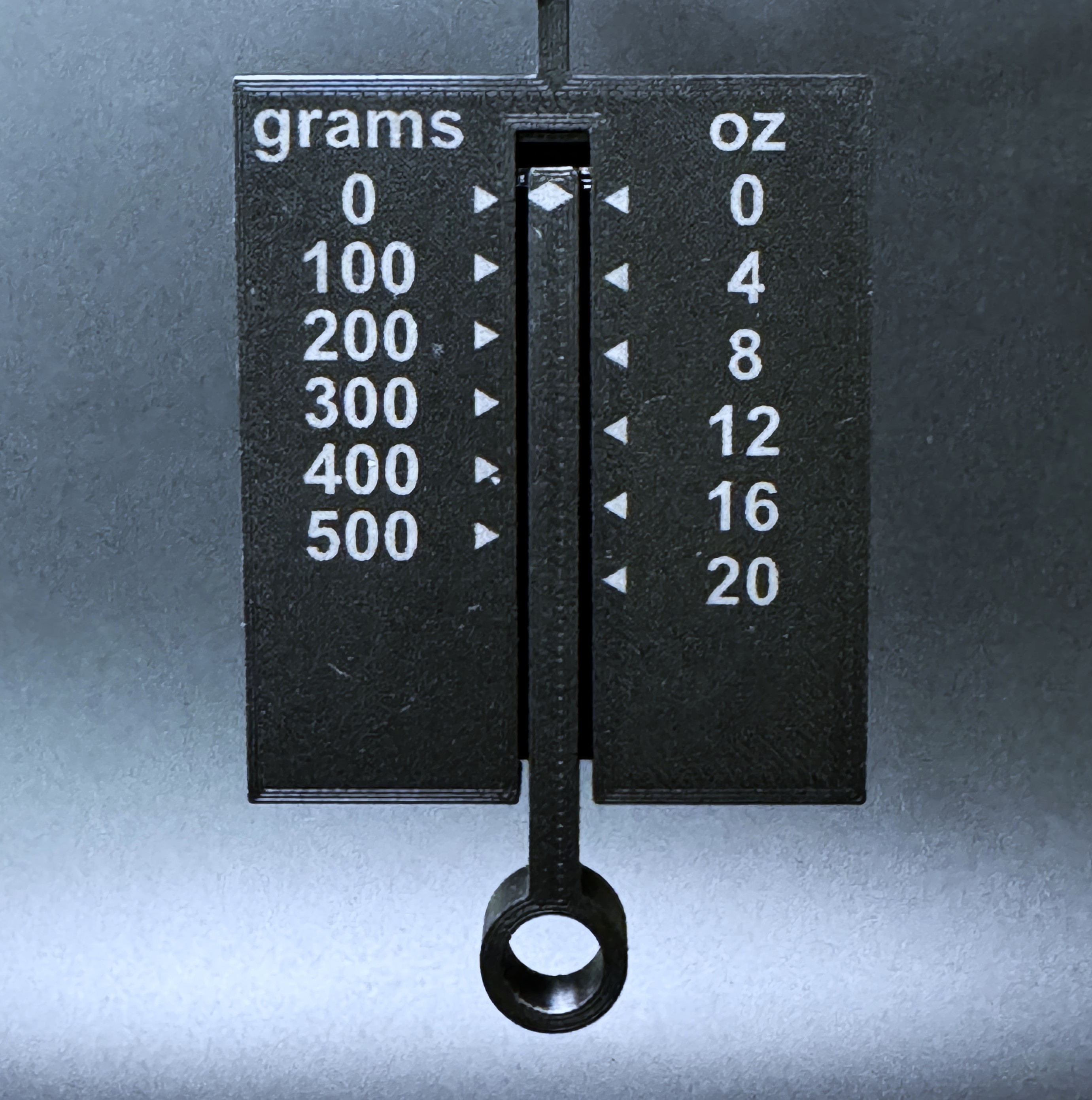 Close up of the tension gauge, marked 0 to 500 grams on one side and 0 to 20 ounces on the other.