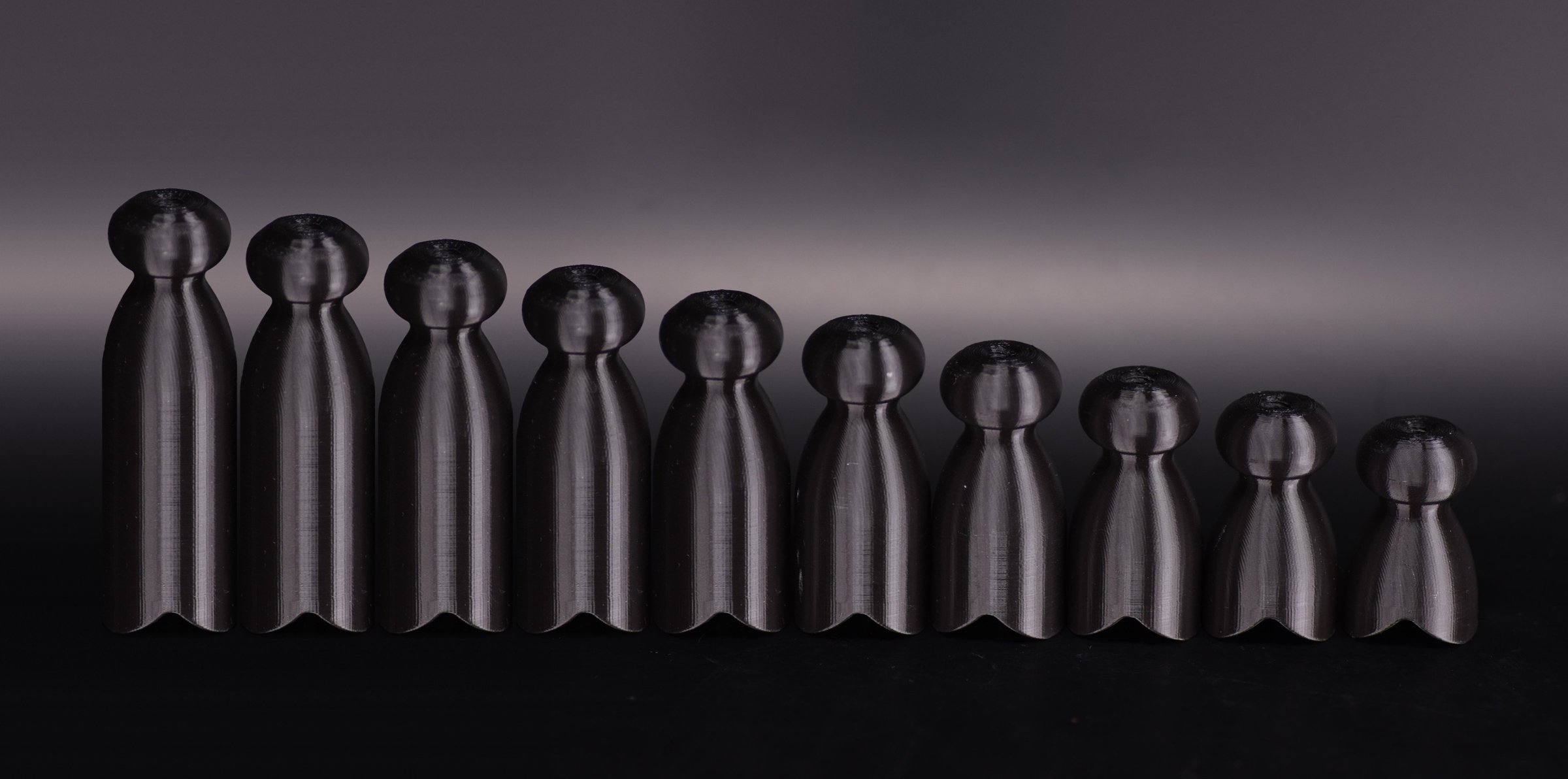 Ten black demo P-tainers in one size lined up from longest to shortest, +50mm down to +5mm.